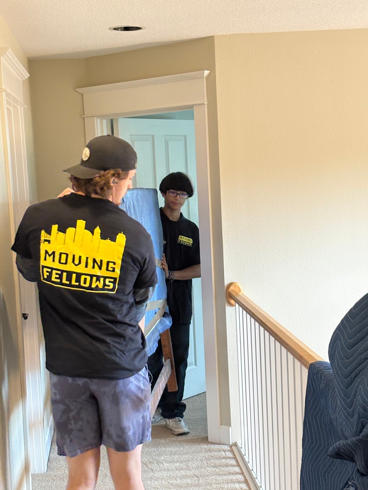 Moving Fellows crew member in a branded shirt carrying a wrapped item through a home